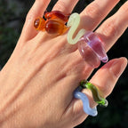 Esto es vidrio, pero no como te lo imaginas. Colores intensos, formas orgánicas, anillos y cadenas contundentes que parecen frágiles, pero se niegan a romperse. Cada pieza está hecha a mano, haciendo que cada curva y cada burbuja sean únicas.
Es divertido, es atrevido, es irreverente.